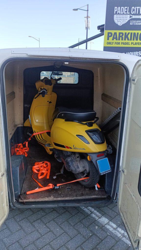 Ophalen gele snorscooter Vespa Sprint Ijet met lekke band bij vliegveld Rotterdam-The Hague Airport.